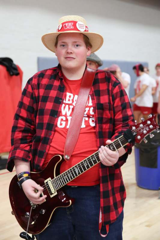 a man wearing a hat and holding a guitar