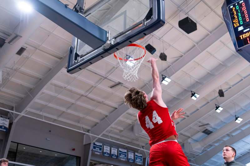 a man in red uniform dunking a basketball hoop