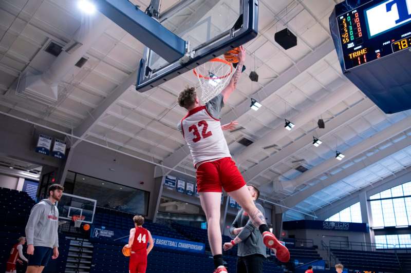 a man in red shorts dunking a basketball in a gym