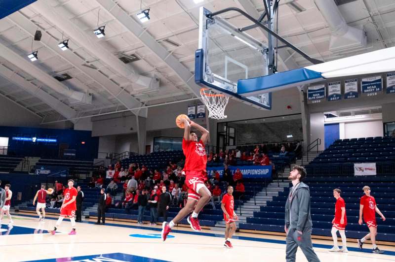 a man in red uniform jumping to dunk in a basketball court