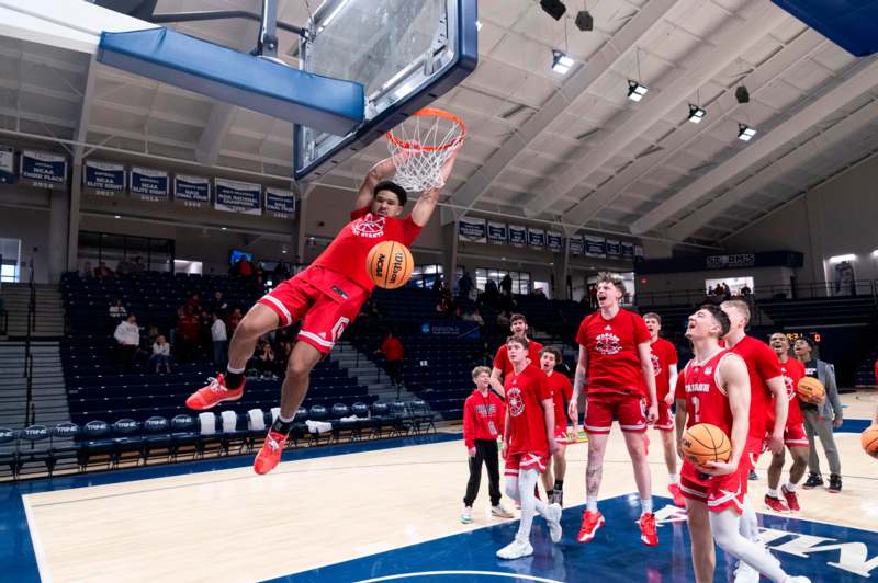 a basketball player in red uniform jumping to dunk a basketball