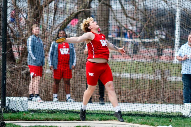a person in red uniform throwing a discus