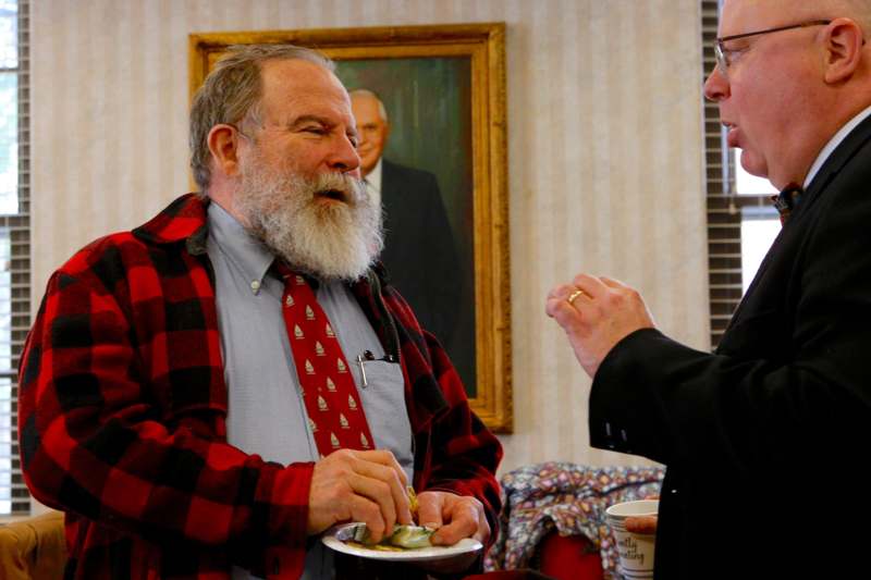 a man in a red flannel shirt and tie holding a plate of food