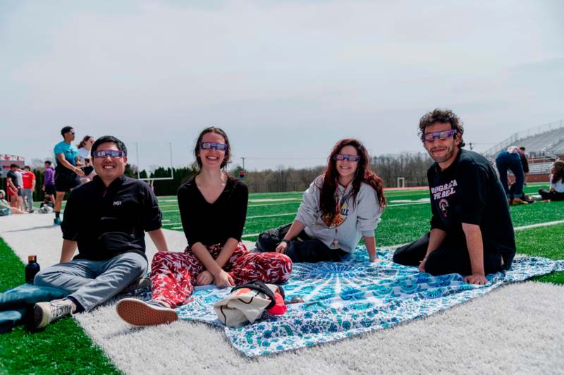 a group of people sitting on a blanket on a field