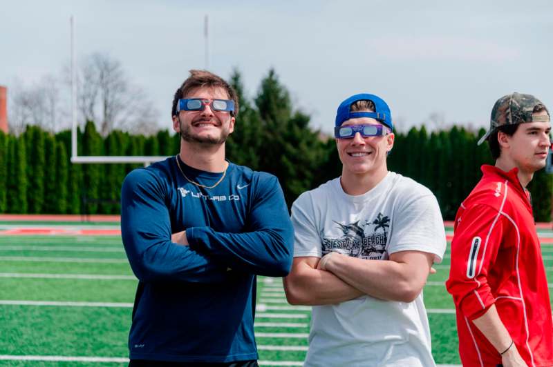 two men wearing blue glasses and standing on a field