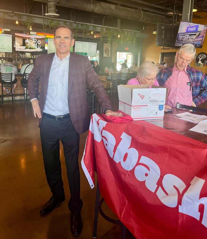 a man standing next to a table with a red banner