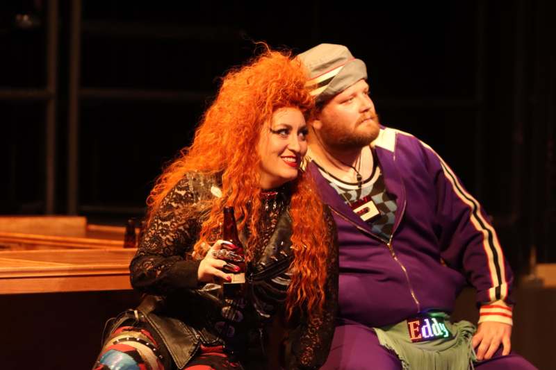 a woman with red hair sitting next to a man with a beer