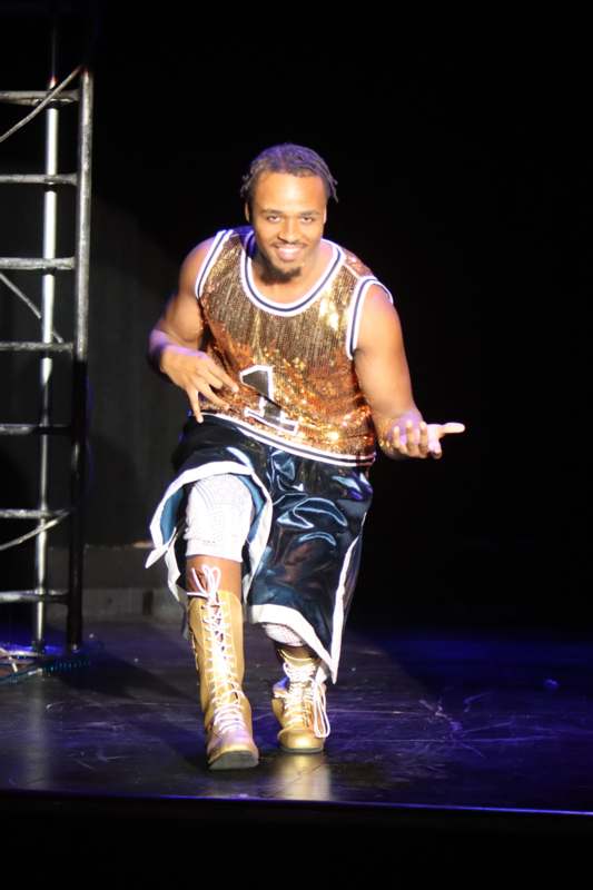 a man in a gold shirt and shorts on a stage