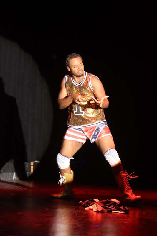 a man wearing a gold shirt and red boots