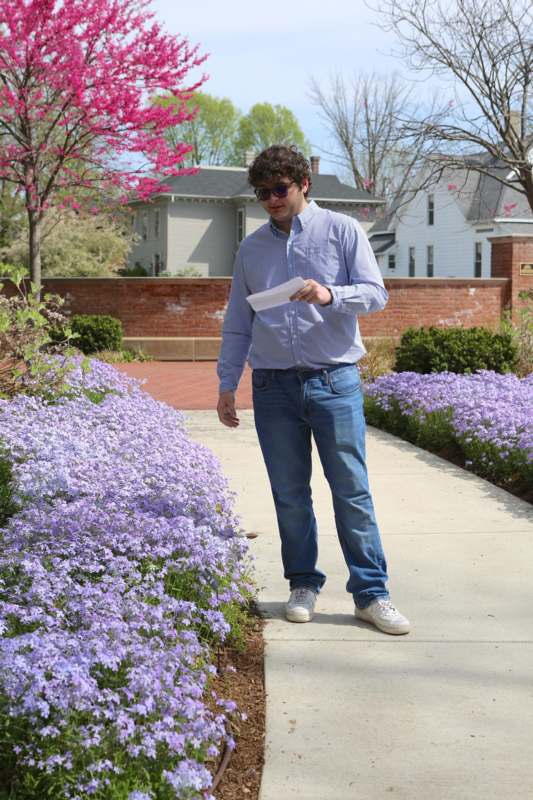 a man standing on a sidewalk holding a paper