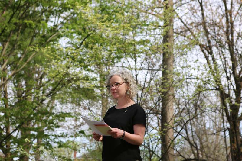 a woman holding a piece of paper in front of trees