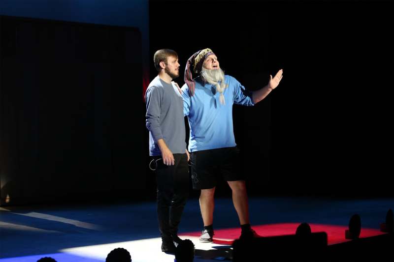 a man standing on a stage with another man standing on a stage