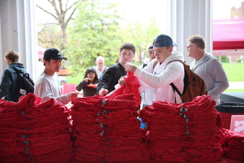 a group of people standing next to stacks of red blankets