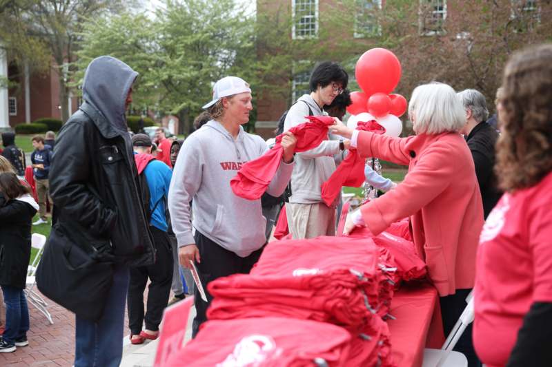 a woman handing a red shirt to a group of people