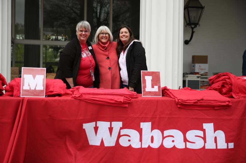 a group of women standing next to a table with red cloth