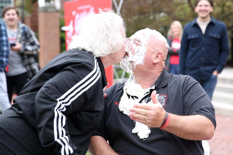 a woman kissing a man with whipped cream on his face