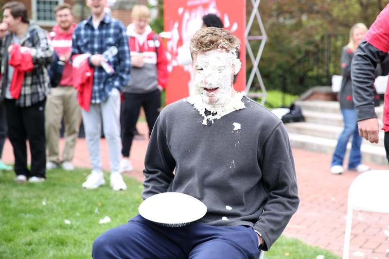 a man with cream on his face sitting on a chair with a plate in his hand