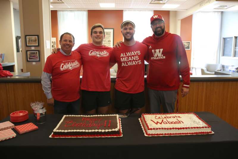 a group of men standing in front of a table with cakes