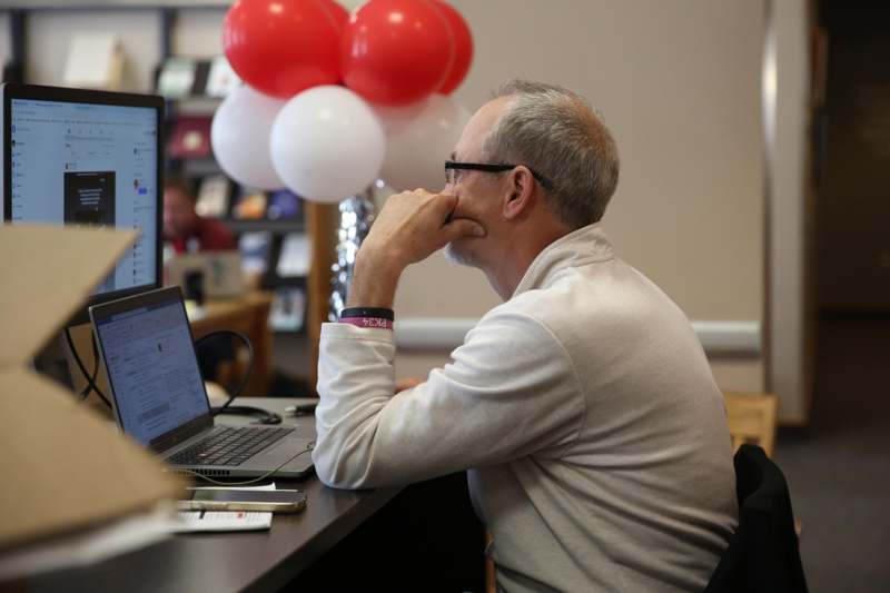 a man sitting at a desk with a laptop and balloons