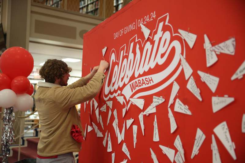 a man writing on a large red banner