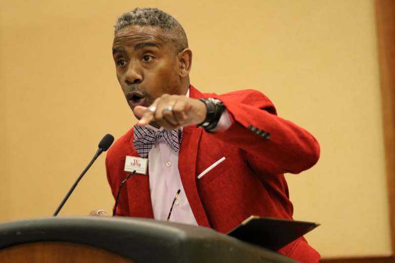 a man in a red suit speaking at a podium