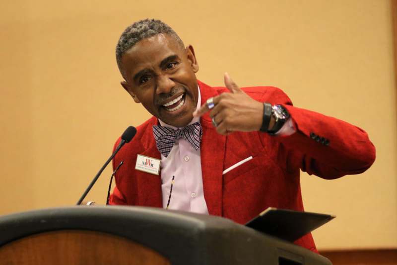 a man in a red suit pointing at a microphone