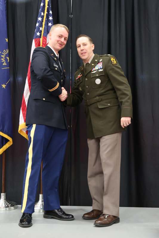two men shaking hands in front of a flag
