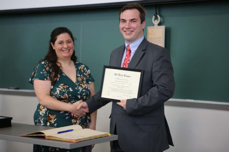 a man in a suit holding a certificate and shaking hands with a woman