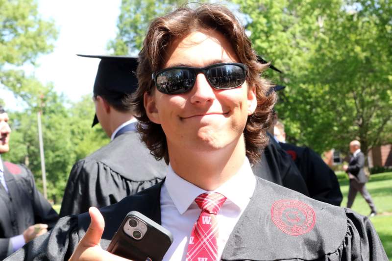 a man wearing a graduation gown and holding a cell phone