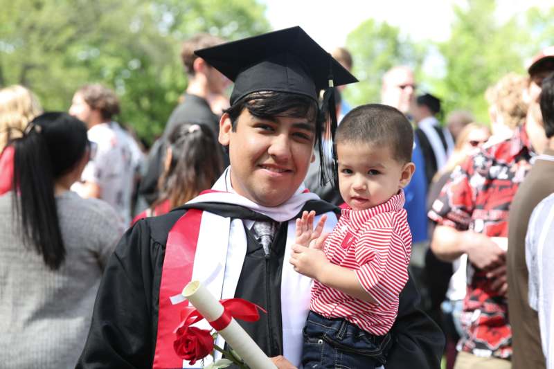 a man in a graduation gown holding a child