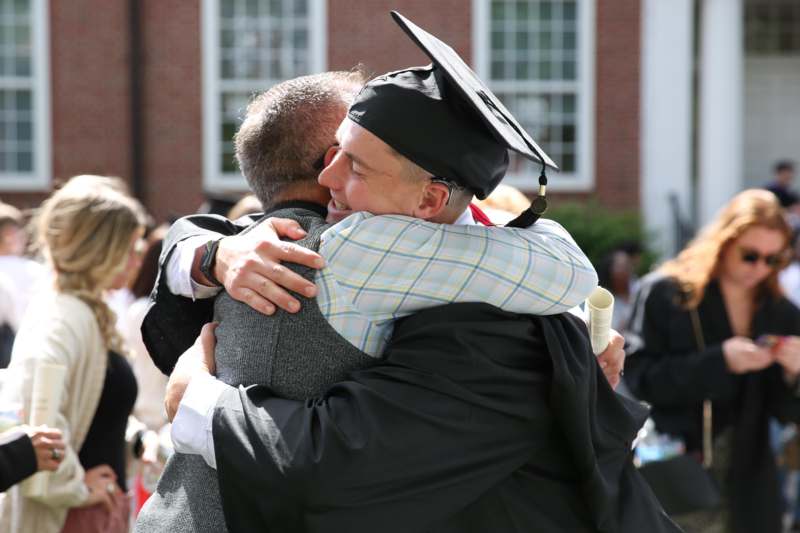 a man in a graduation cap and gown hugging another man