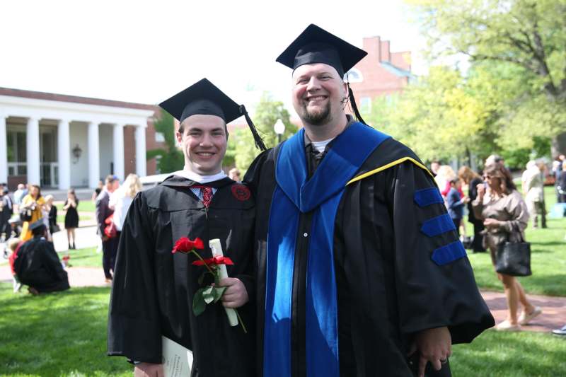 a man in cap and gown standing next to a man in cap and gown