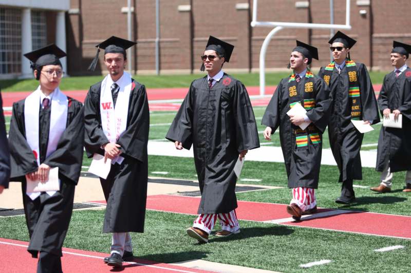 a group of people in graduation gowns walking on a track