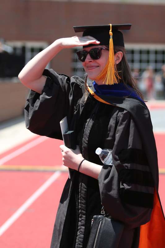 a woman in a graduation gown saluting