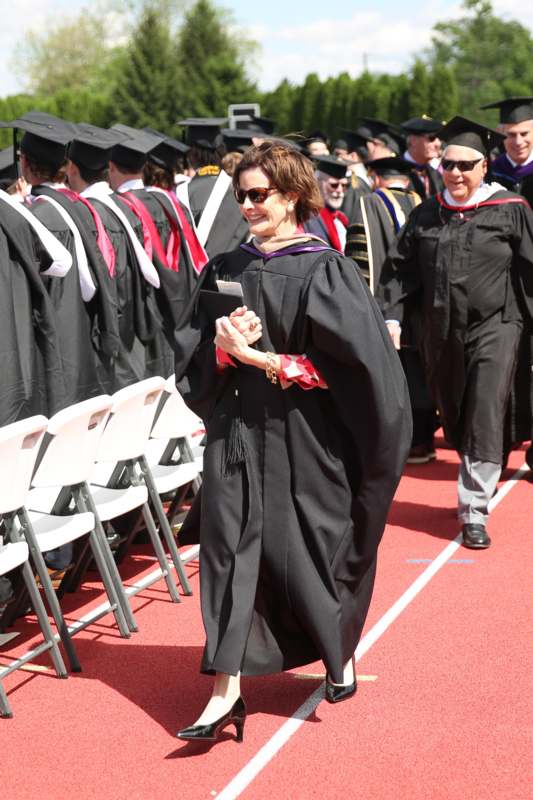 a woman in a black robe walking in a row of people