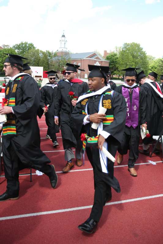 a group of people in graduation gowns and caps walking on a track