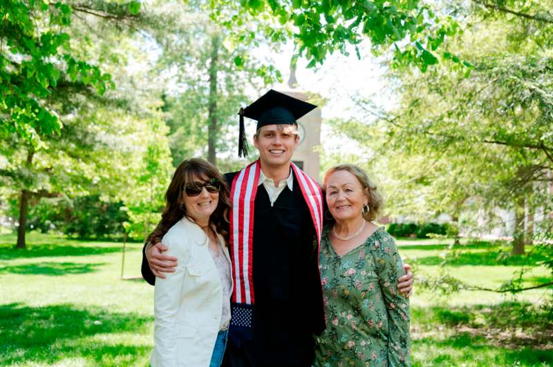 a man in a cap and gown with two women in a park