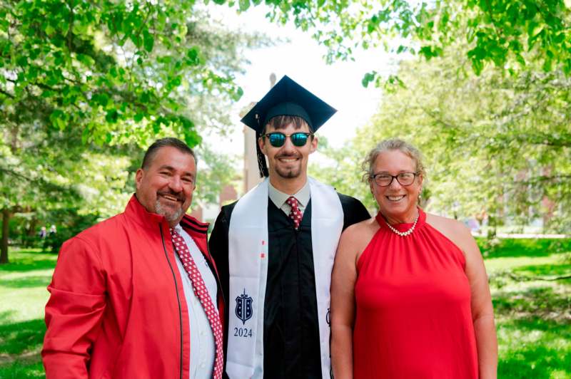 a man in a graduation cap and gown with a woman and a man in a red dress