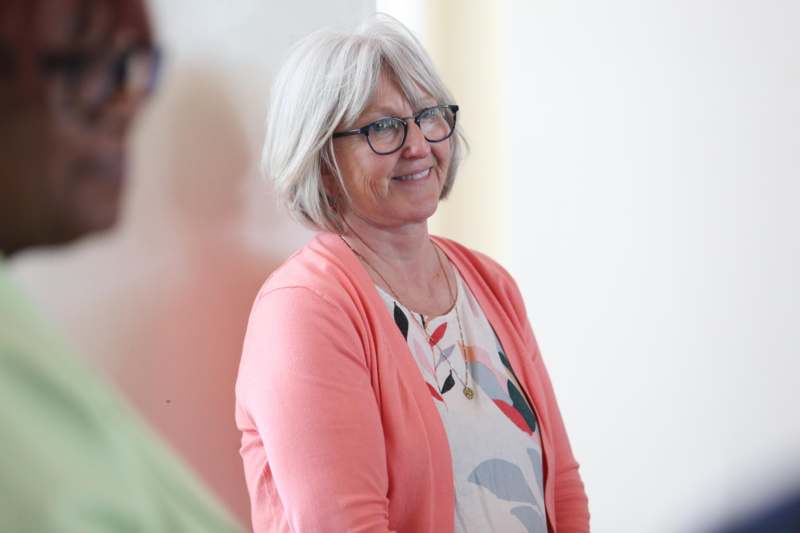 a woman wearing glasses and a pink cardigan