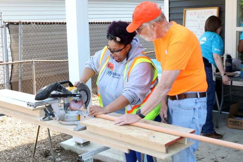 a man and woman working on a wood plank