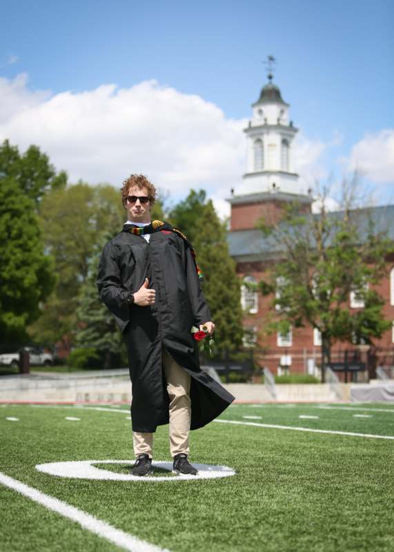 a man in a graduation gown standing on a football field