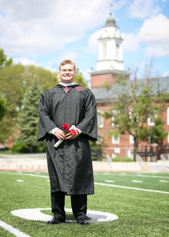 a man in a graduation gown holding flowers