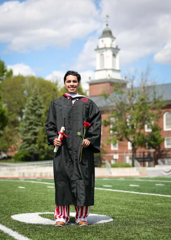 a man in a graduation gown holding roses