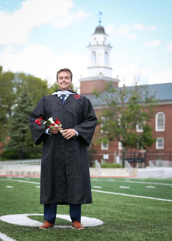 a man in a graduation gown holding flowers