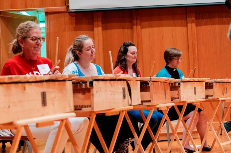 a group of people sitting in a row of wooden boxes