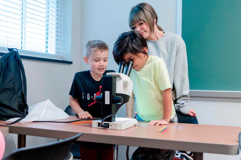 a woman and two children looking through a microscope