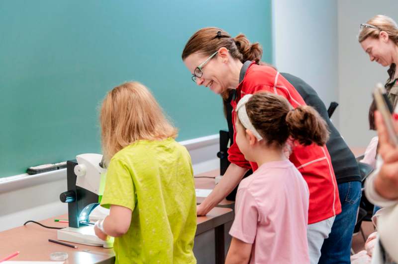 a woman and kids looking at a microscope