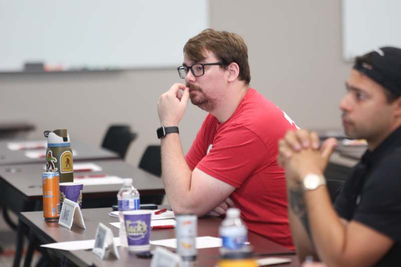 a man in a red shirt sitting at a table with other people