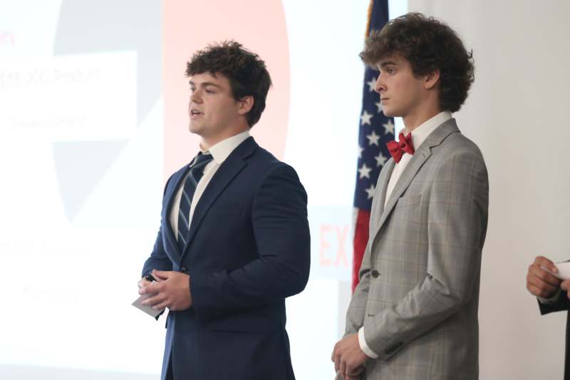 two men in suits standing in front of flags