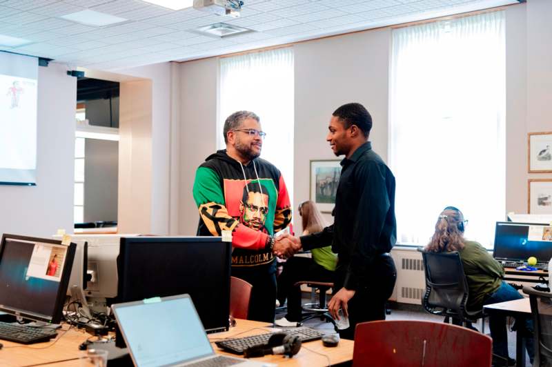 a man shaking hands with another man in an office